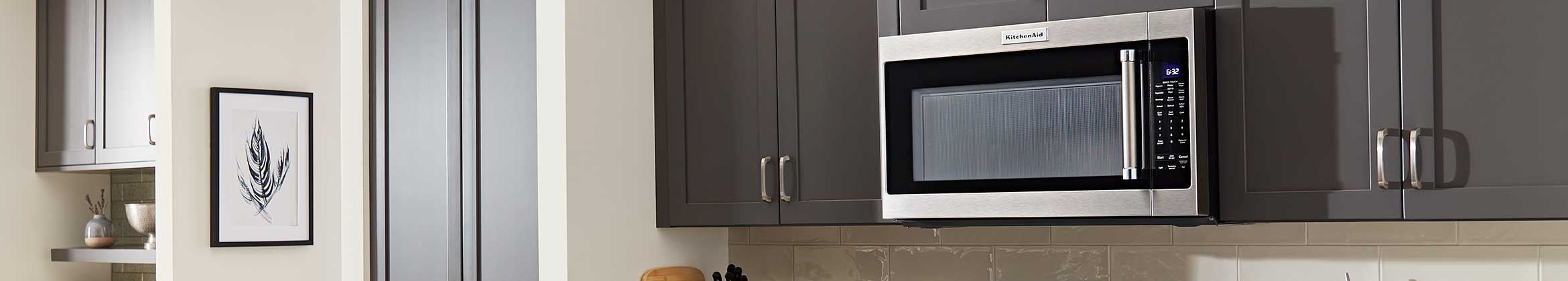 A stainless steel KitchenAid microwave surrounded by cabinets