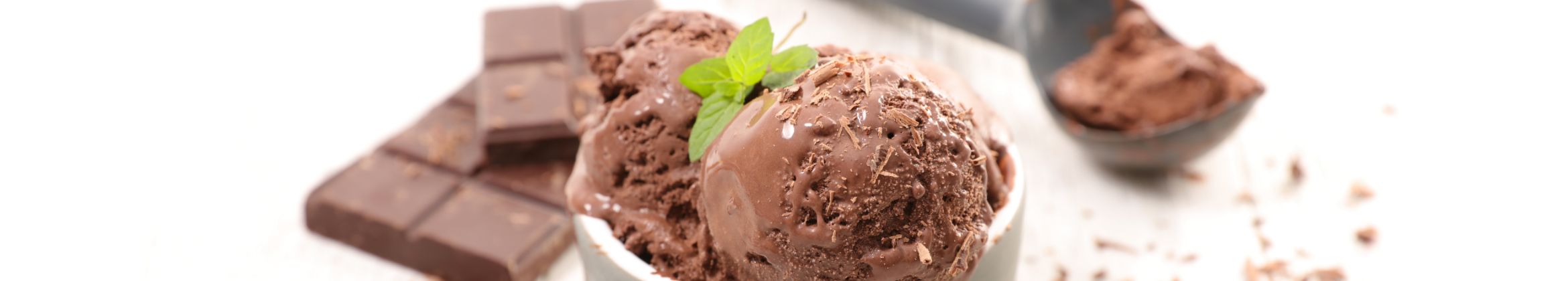 A bowl of chocolate ice cream with chocolate bars in the background.