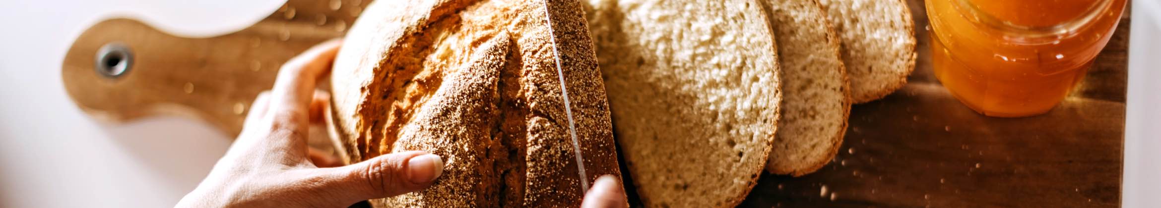 Crusty bread being sliced on countertop