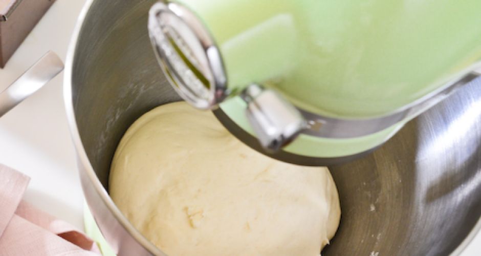 A large metal mixing bowl attached to the KitchenAid Stand Mixer reveals the captivating sight of dough rising gracefully within.