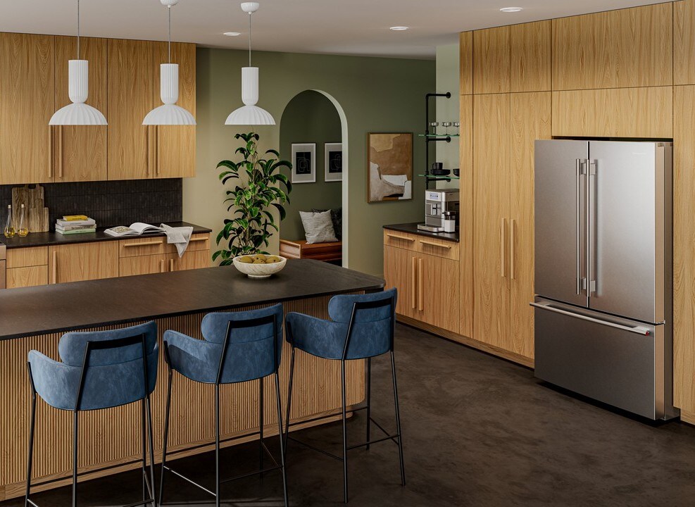 A kitchen with a KitchenAid French door refrigerator near an island with three blue stools.