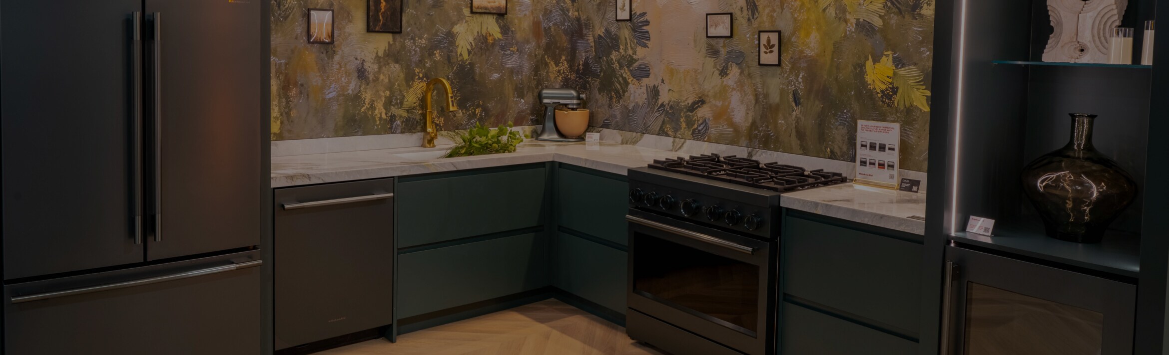A stunning kitchen with KitchenAid appliances like a refrigerator, dishwasher, and range. There are grey cabinets and a KitchenAid stand mixer on the counter.