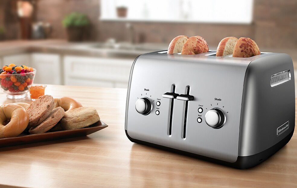 A person toasting bread and bagels in a KitchenAid® 4-Slice Toaster.