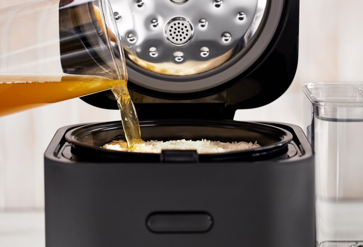 Broth being poured into the grain and rice cooker.