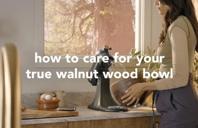 A person holding the true walnut bowl of the Evergreen stand mixer