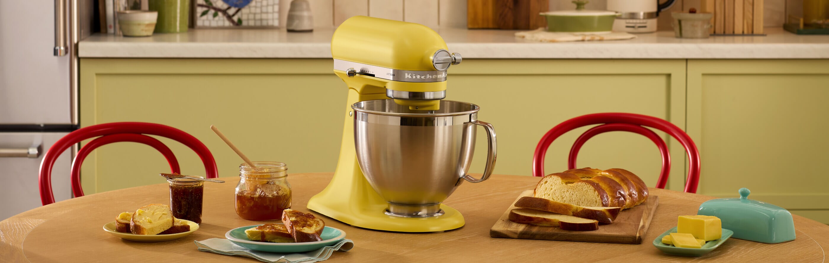 The Butter Stand Mixer surrounded by jams, breads and butter. Intro: The Color of the Year 2025 Stand Mixer in Butter, with butter in the bowl.