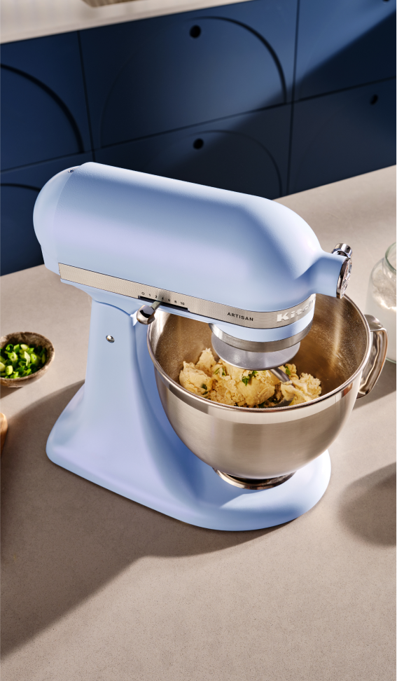 A Blue Salt Stand mixer with ingredients in the bowl.