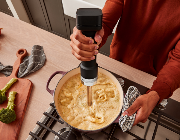 A person using a KitchenAid® Cordless Immersion Blender.