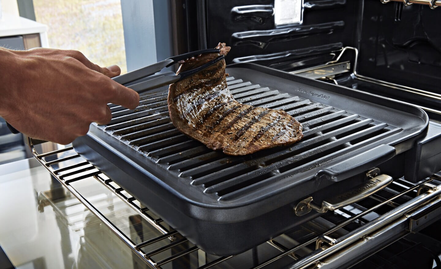 A person grilling a steak in an oven