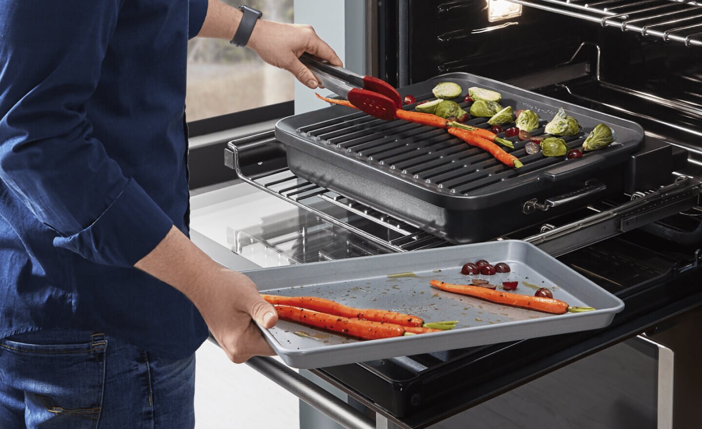 A person grilling vegetables in a KitchenAid® oven