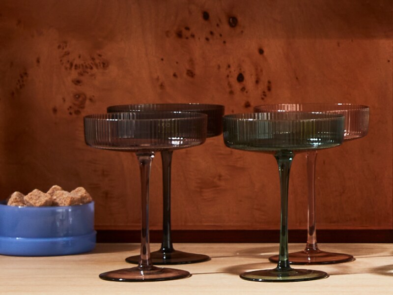 Four empty martini glasses and a small blue container of brown sugar cubes. 