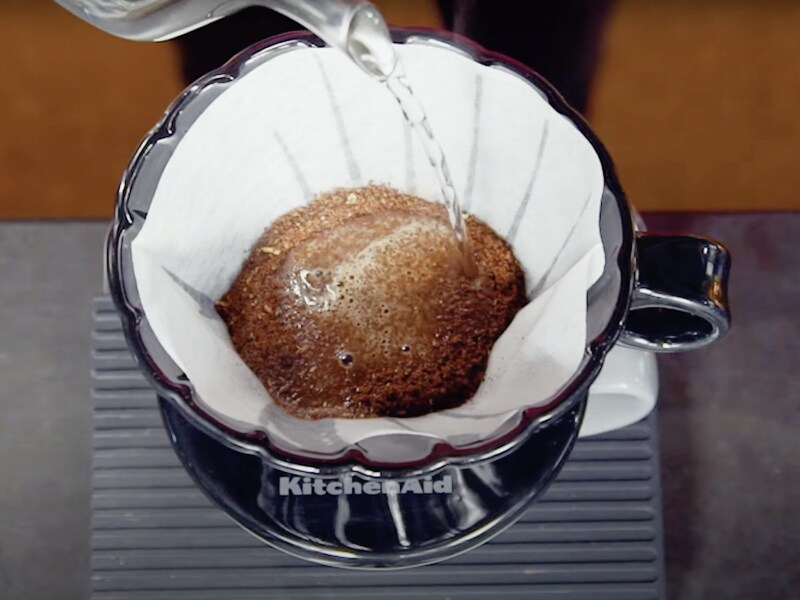 Vue de dessus d'eau bouillante ajoutée au café moulu dans un filtre de café à verser.