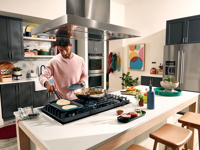 Une personne cuisine sur l'accessoire de plaque chauffante d'une cuisinière au gaz