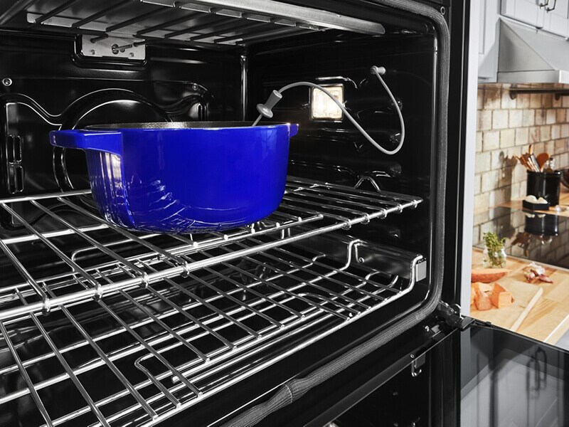 Blue casserole dish in an oven with a temperature monitor in it