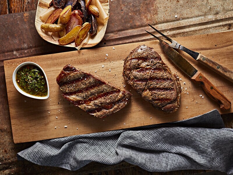Two pieces of cooked steak on a cutting board