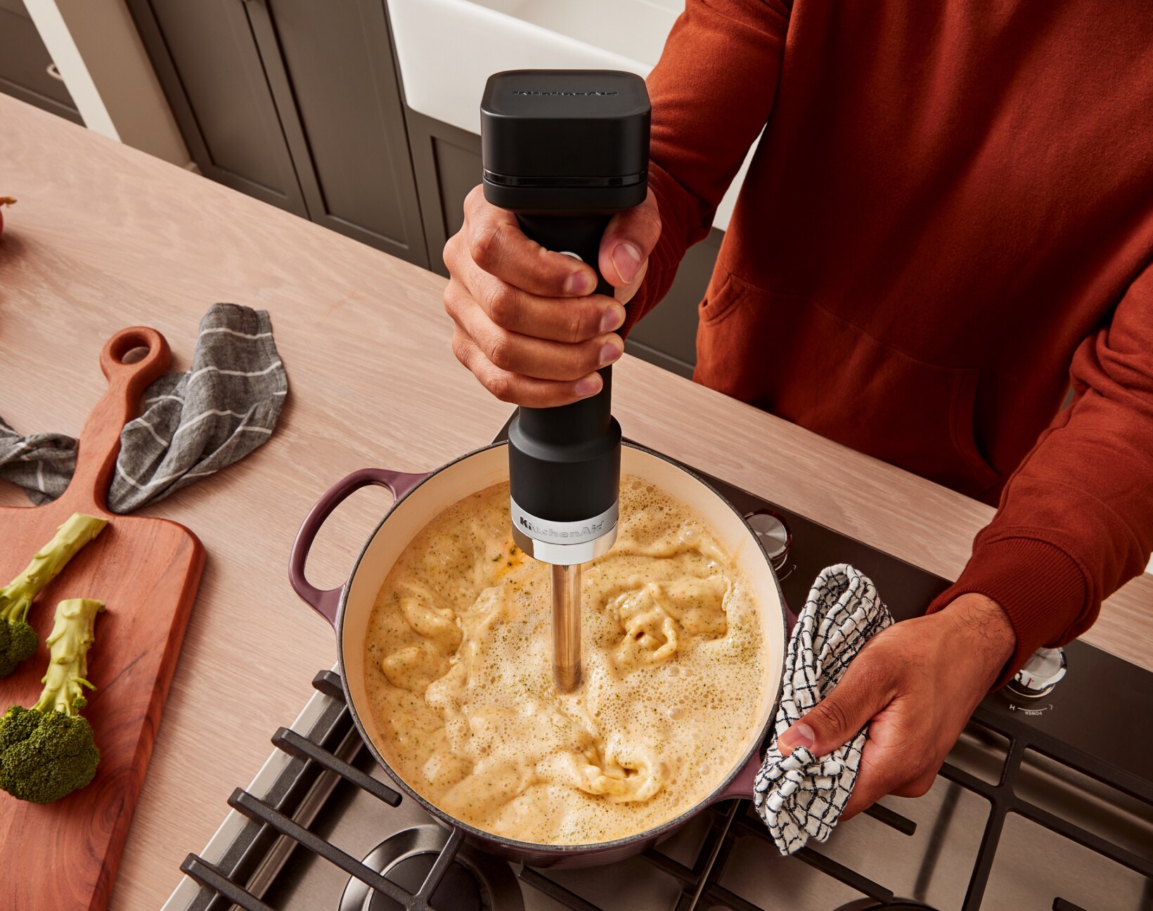 Une personne utilisant le mélangeur à main sans fil KitchenAid Go™ pour mélanger de la soupe.