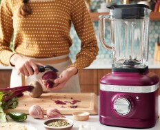 A KitchenAid® Grain and Rice Cooker on a white countertop, behind it a green backsplash.