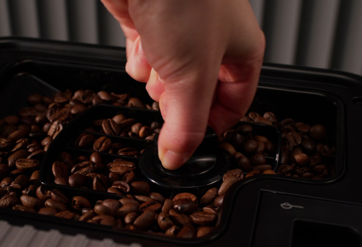 Person removing a bean hopper from an espresso machine