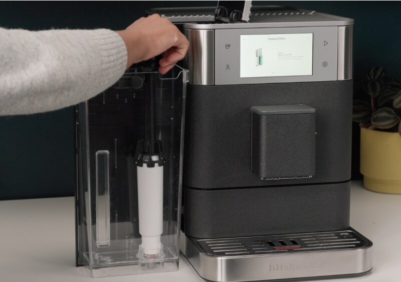 Person changing the water filter from an espresso machine