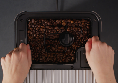 Person removing the bean hopper from an espresso maker
