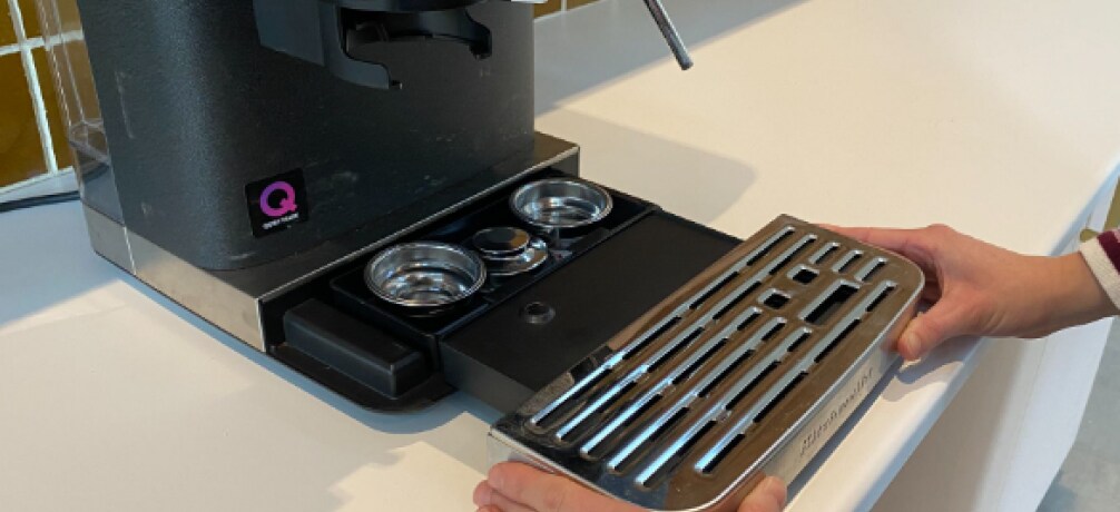 Person removing an espresso machine drip tray