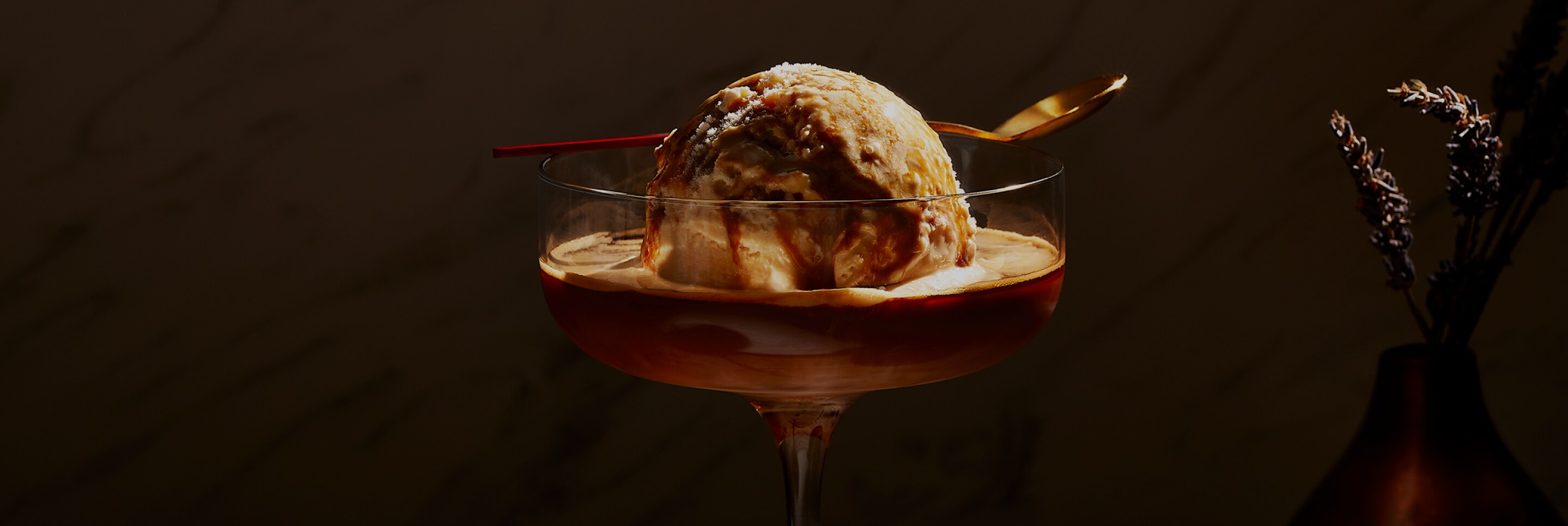 A close up image of a large scoop of vanilla ice cream with a shot of espresso poured over.