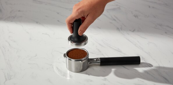 Person tamping espresso in a portafilter