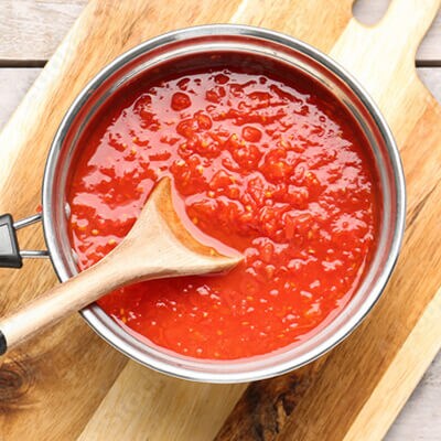Une personne remuant de la sauce dans une casserole