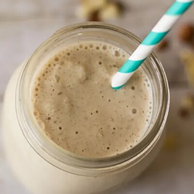 A vanilla drink in a mason jar with a blue and white straw