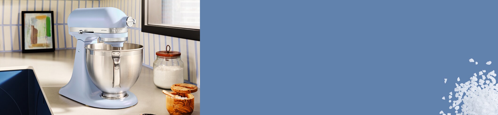 An Artisan® Stand Mixer in Blue Salt on a countertop, with different baking ingredients around the mixer.