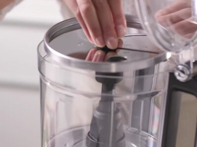 A user opening a food processor and adding blade.