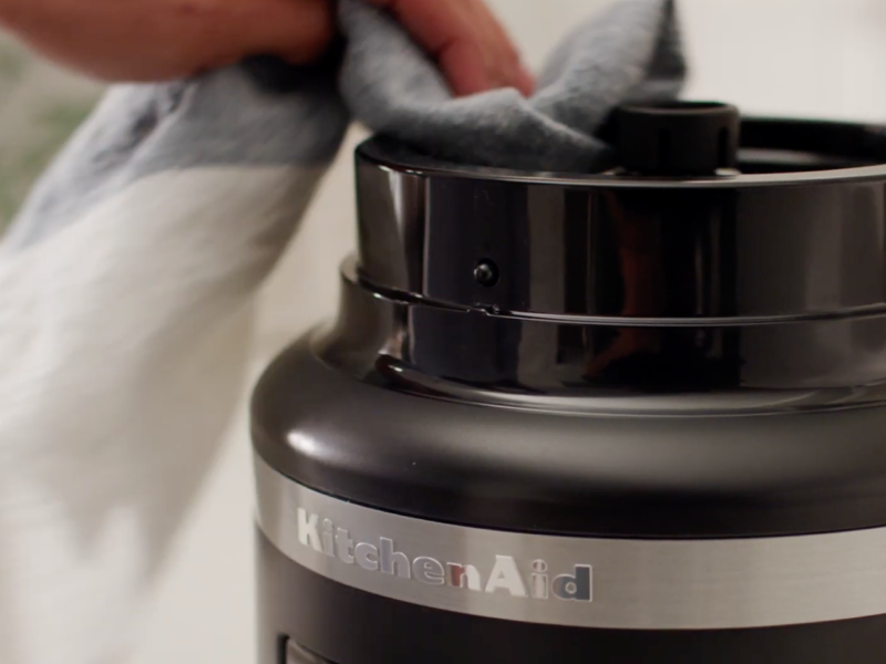 A person cleaning the base of a disassembled food processor