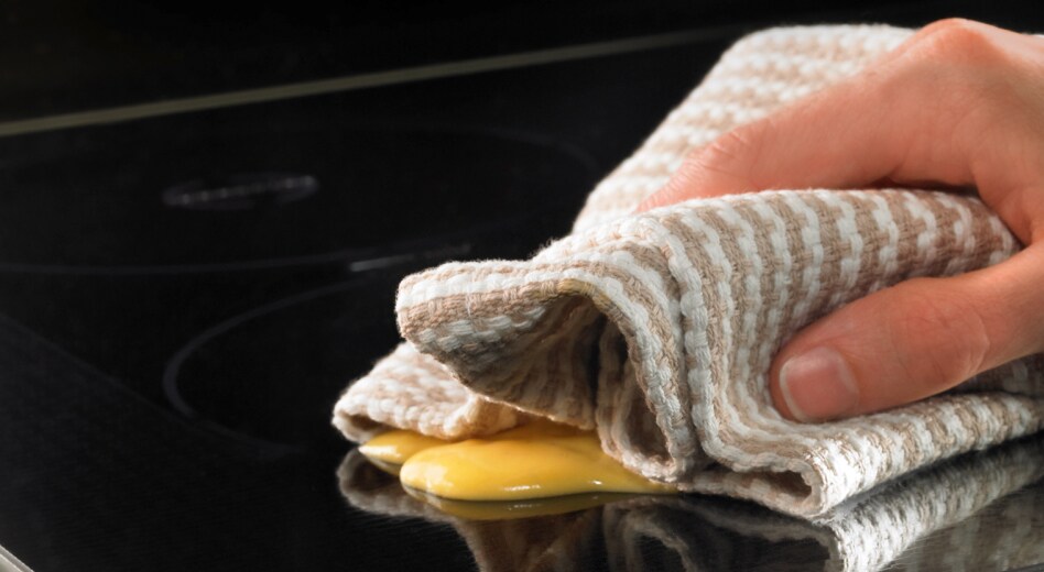 A person wiping down a cooktop surface.