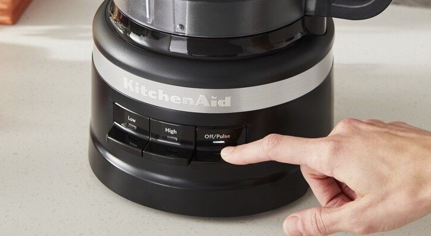 Hand pressing pulse button on a food processor