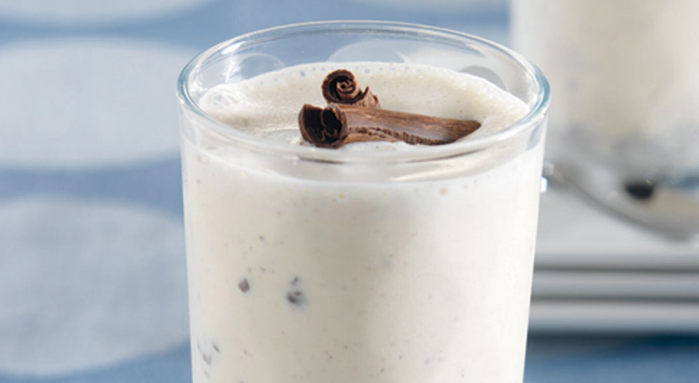Close-up of vanilla milkshake with mix-ins and cinnamon sticks on top