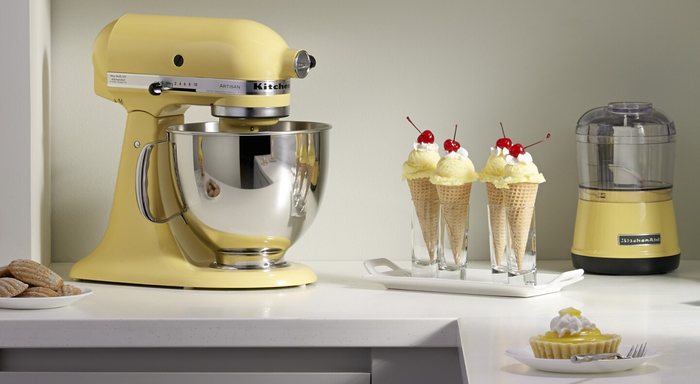 A yellow KitchenAid® stand mixer next to ice cream in waffle cones