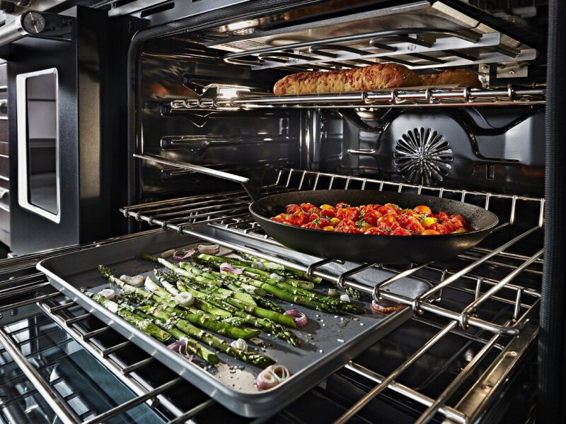 Asparagus, vegetables and bread cooking on separate racks in the oven