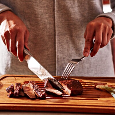 Une personne tranchant un steak