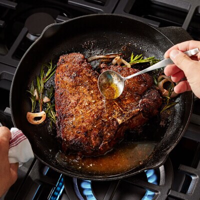 Une personne arrosant un steak