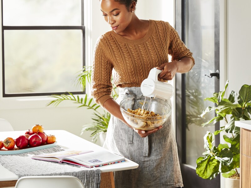 Person using KitchenAid® hand mixer and reading instructions