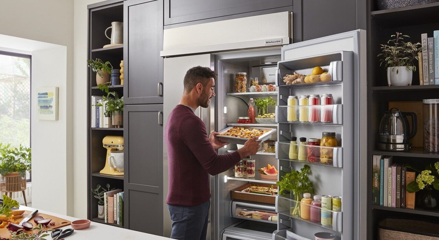 Person removing food from a side-by-side refrigerator