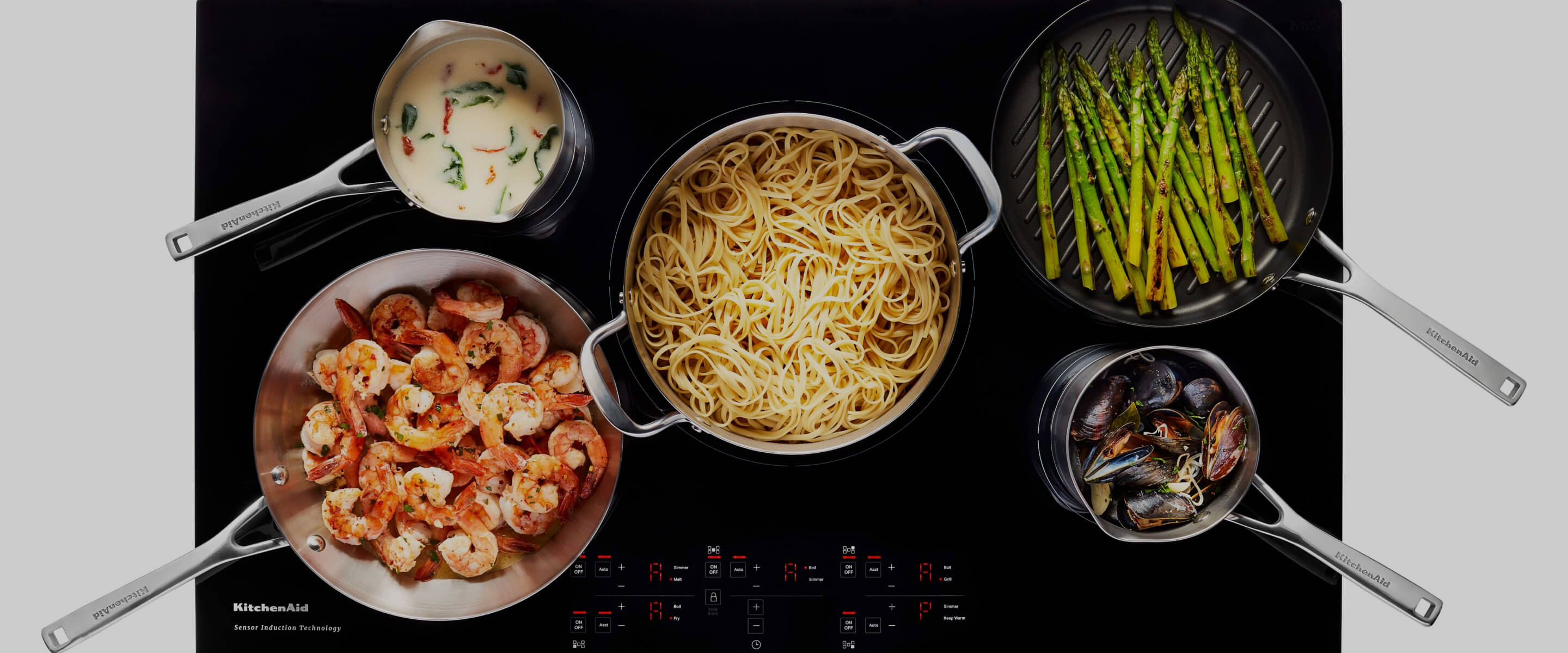 A variety of dishes cooking on an induction cooktop.