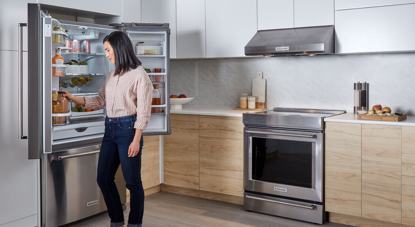  Personne regardant à l’intérieur d’un réfrigérateur à portes françaises KitchenAid®