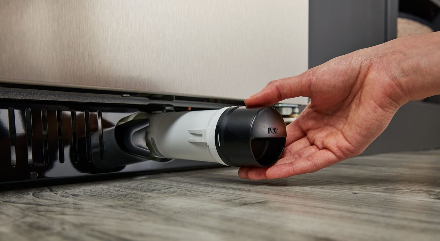 Une personne retire le filtre à eau d’un réfrigérateur