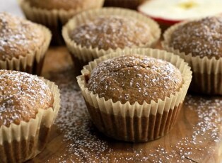 A basket of muffins with chopped nuts on top.