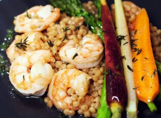 A plate of steamed shrimp served with couscous, asparagus and heirloom carrots.