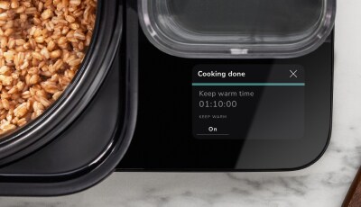 A close up of the touchscreen's keep warm function, with cooked grains in the pot of the Grain and Rice Cooker.