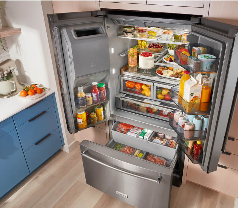 A fully loaded KitchenAid® French Door Bottom Mount Refrigerator with the doors and drawers open.
