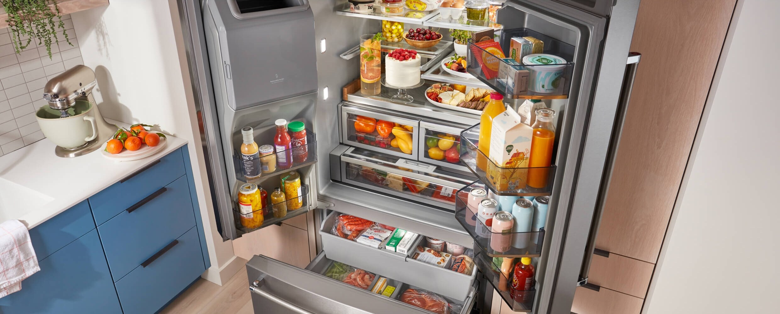 A fully loaded KitchenAid® French Door Bottom Mount Refrigerator with the doors and drawers open.