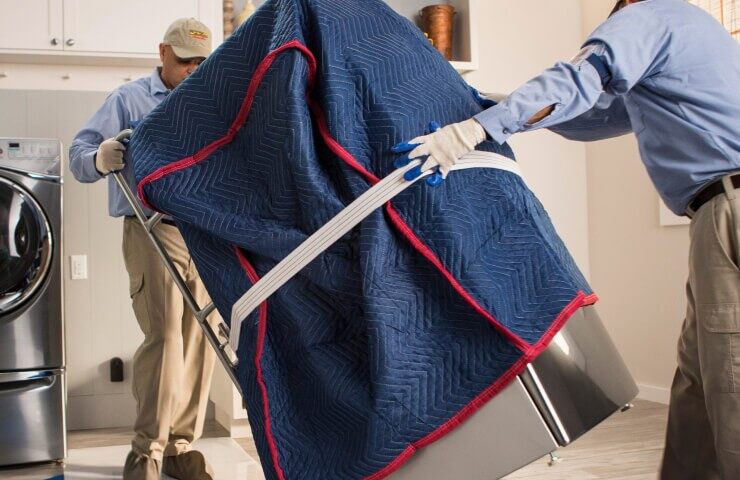 Two people install a new laundry machine in a laundry room.